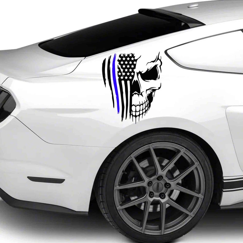 May include: A white car with a black and blue skull and American flag decal on the back fender.