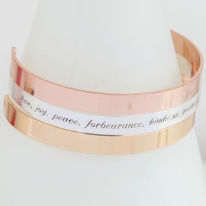 Peut inclure: Un bracelet jonc triple avec une finition or rose, argent et or. La bande argentée est gravée des mots "love, joy, peace, forbearance, kindness, goodness, faithfulness, gentleness, self-control."