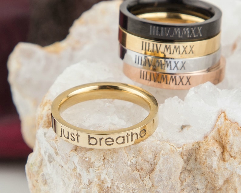 May include: A gold-colored stainless steel ring with the words "just breathe" engraved on the band.