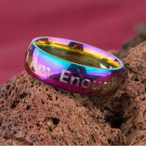 Peut inclure: Une bague en acier inoxydable aux couleurs de l'arc-en-ciel avec les mots "Am Enough" gravés sur la bande.