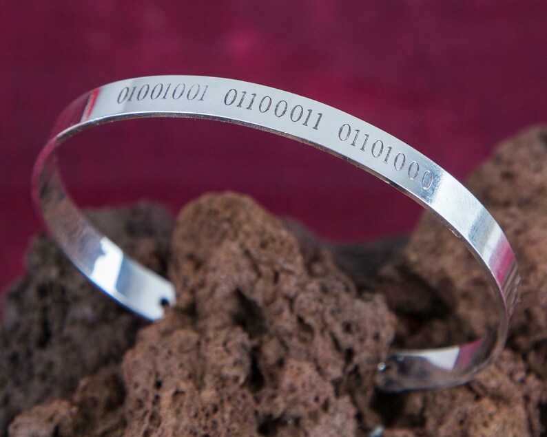 Puede incluir: Un brazalete de plata con el c&oacute;digo binario "01001001 01100011 01101000" grabado en &eacute;l.