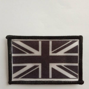 Puede incluir: Parche de bandera Union Jack en blanco y negro con borde negro. El parche está hecho de tela y tiene un borde cosido.