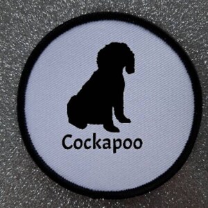 May include: White round patch with a black silhouette of a Cockapoo dog sitting. The text "Cockapoo" is written below the dog.