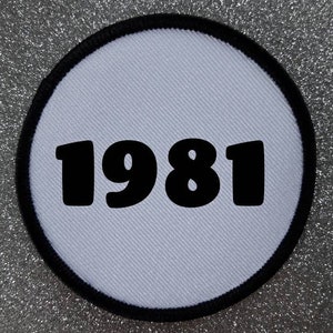 May include: White round patch with a black border and the year 1981 printed in black.