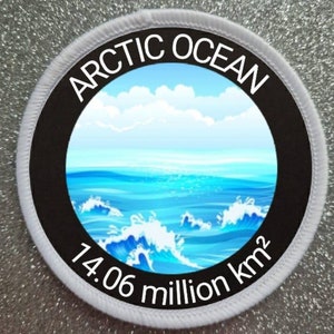 Op de afbeelding: Een witte en zwarte ronde patch met de tekst "ARCTIC OCEAN" in een zwarte cirkel. De cirkel bevat een blauwe oceaan met witte golven en een blauwe lucht met witte wolken. De tekst "14,06 miljoen km²" staat onder de cirkel.