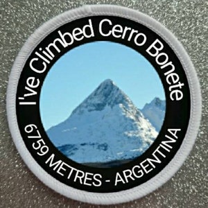 May include: White round patch with black text that reads "I've Climbed Cerro Bonete 6759 Metres - Argentina". The patch features a photo of a snow-capped mountain peak.