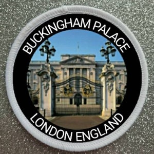 May include: A white round patch with black text and a photo of Buckingham Palace in London, England. The text reads "Buckingham Palace London England".
