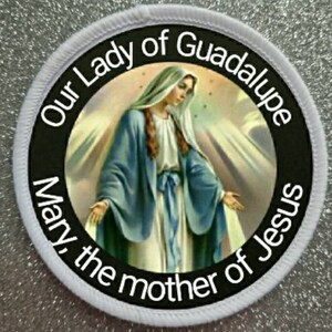 Könnte beinhalten: Runder weißer Aufnäher mit schwarzem Text und einem Bild von Unserer Lieben Frau von Guadalupe. Der Text lautet "Unsere Liebe Frau von Guadalupe Maria die Mutter Jesu".