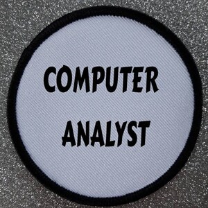 Może przedstawiać: Okrągła biała łatka z czarnym obszyciem. Tekst "COMPUTER ANALYST" jest nadrukowany czarnym kolorem.