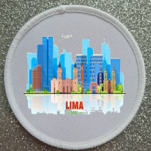 May include: White round patch with a colorful cityscape of Lima, Peru. The city skyline is reflected in the water below. The text "LIMA - PERU" is printed below the cityscape.