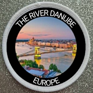 May include: A white circular patch with black trim and a photo of the Danube River in Budapest, Hungary. The text "THE RIVER DANUBE EUROPE" is printed around the photo.