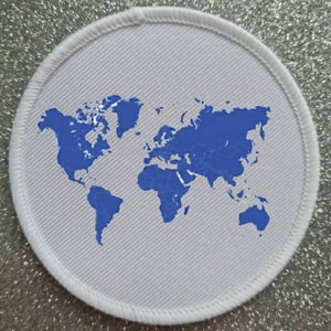 May include: A white round patch with a blue outline and a blue world map design.