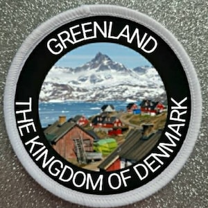 May include: White round patch with black text that reads "Greenland The Kingdom of Denmark" around a colorful image of a snowy mountain range and a village.