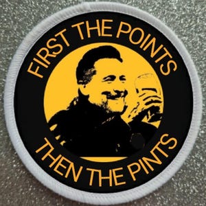 Può includere: Un cerotto circolare bianco con testo nero che recita "First the points then the pints" attorno a un'immagine in bianco e nero di un uomo che tiene un bicchiere di birra.