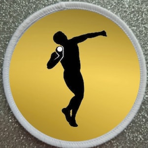 May include: A white circle patch with a gold background and a black silhouette of a person throwing a shot put.