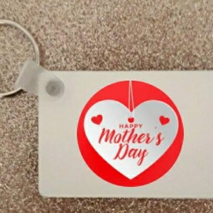 Könnte beinhalten: Weißer Schlüsselanhänger mit einem roten herzförmigen Design. Das Herz hat ein kleineres weißes Herz im Inneren und den Text "Frohe Muttertag".