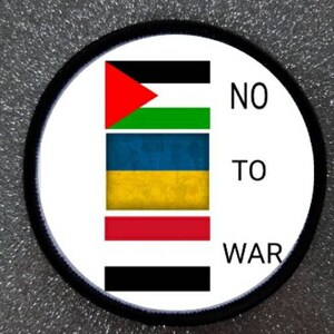 May include: A white circle patch with black trim, featuring the flags of Palestine, Ukraine, and Russia stacked vertically. The text "NO TO WAR" is printed in black on the right side of the patch.
