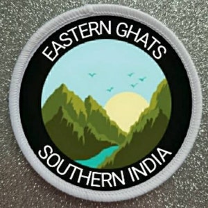 May include: White round patch with black border and white text that reads "Eastern Ghats Southern India". The center of the patch features a green mountain range with a blue river and a yellow sun.