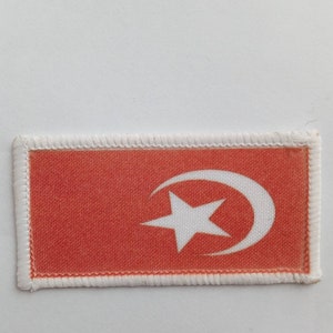 Könnte beinhalten: Ein roter Stoff-Patch mit einem weißen Halbmond und Stern.