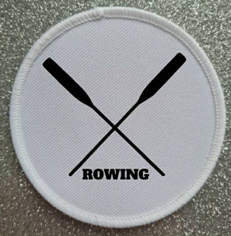 May include: White round patch with black embroidered crossed oars and the word "ROWING" underneath.