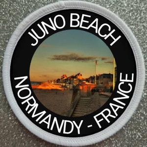 May include: A black and white circular patch with the text "Juno Beach Normandy - France" around a photo of a beach scene with buildings in the distance.