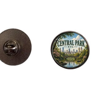 Pode incluir: Pin redondo com uma imagem detalhada do Central Park em Nova York. O pin apresenta uma vista panorâmica do parque com uma ponte, água e o horizonte da cidade. O pin tem um verso de metal preto.