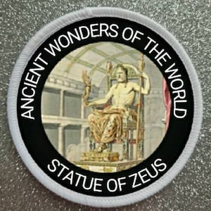 May include: A black and white circular patch with the text "Ancient Wonders of the World" and "Statue of Zeus" around a depiction of the Statue of Zeus, one of the Seven Wonders of the Ancient World.