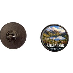May include: A round enamel pin featuring a scenic landscape of Angle Tarn in the Lake District. The pin has a black border and the text "ANGLE TARN - LAKE DISTRICT". The pin is approximately 1 inch in diameter.