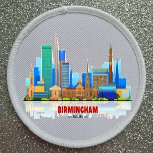 May include: White oval fabric patch featuring a colourful cityscape design of Birmingham, England. The text "BIRMINGHAM - ENGLAND" is printed in red below the cityscape.