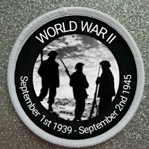 May include: Black and white circular patch with white stitching around the edge. The patch features a silhouette of three soldiers in a field with the text "World War II September 1st 1939 - September 2nd 1945".