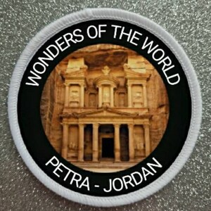 May include: A white circular patch with black text and a black circle in the center. The text reads "Wonders of the World" and "Petra - Jordan". The black circle contains a photo of the Treasury in Petra, Jordan.