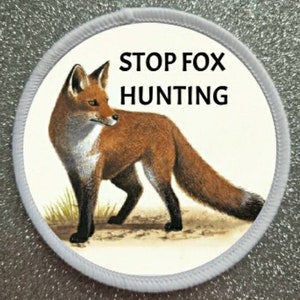 May include: A white round patch with a red fox illustration and the text "STOP FOX HUNTING" in black.