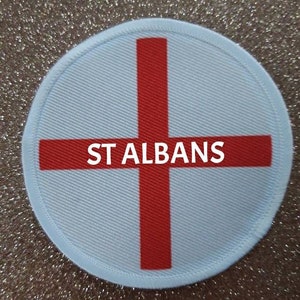 May include: A white round patch with a red cross and the text "ST ALBANS" in the centre.