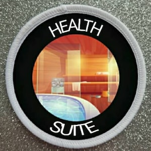 Könnte beinhalten: Runder weißer Patch mit schwarzem Rand und dem Text "HEALTH SUITE" in Weiß. Der Patch zeigt eine Fensteransicht einer Sauna mit einem Wasserbecken.