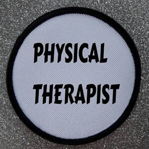 以下が含まれることがあります： 黒い縁取りのある白い丸いパッチで、黒い太字で「PHYSICAL THERAPIST」と書いてあります。