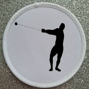 May include: White round patch with a black silhouette of a person throwing a hammer.