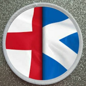 Może przedstawiać: Okrągła biała łatka z flagami Anglii i Szkocji zszytymi razem. Flaga angielska znajduje się po lewej stronie, a flaga szkocka po prawej. Flagi są zszyte razem w środku.