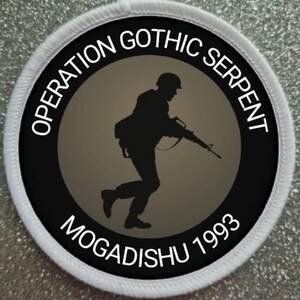 May include: A circular patch with the text "OPERATION GOTHIC SERPENT MOGADISHU 1993" encircling a silhouette of a soldier running with a rifle. The patch has a black border and a gray background.