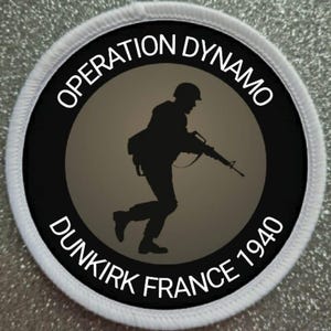 May include: A circular patch with the text "OPERATION DYNAMO DUNKIRK FRANCE 1940" in white lettering. The patch features a black silhouette of a soldier running with a rifle against a gray background.
