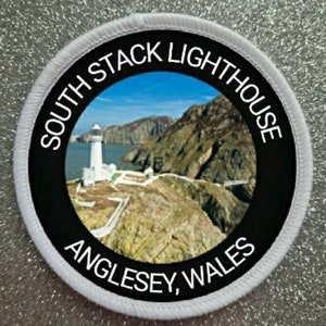 May include: Circular patch depicting the South Stack Lighthouse in Anglesey, Wales. The design includes a white lighthouse on a cliff, with the text "SOUTH STACK LIGHTHOUSE ANGLESEY, WALES" in a circular arrangement.