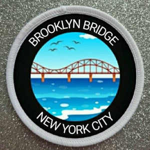 May include: A white round patch with black text and a black circle in the center. The text reads "Brooklyn Bridge New York City". The black circle contains a cartoon image of the Brooklyn Bridge over blue water.