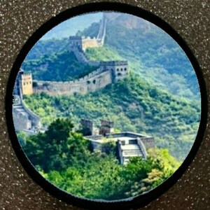 May include: A panoramic view of the Great Wall of China, a UNESCO World Heritage Site, winding through a mountainous landscape. The wall is made of stone and brick and is surrounded by lush green vegetation.