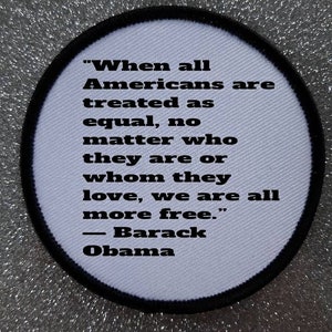 May include: A white circular patch with a black border and text that reads "When all Americans are treated as equal, no matter who they are or whom they love, we are all more free." - Barack Obama