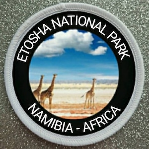 May include: White round patch with black text and a photo of giraffes in a savanna. The text reads "Etosha National Park Namibia - Africa".