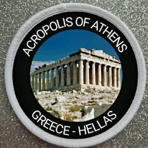 Puede incluir: Un parche circular blanco y negro con el texto "ACROPOLIS DE ATENAS GRECIA - HELLAS" alrededor de una foto de la Acrópolis en Atenas, Grecia.
