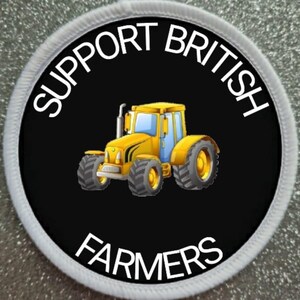 Op de afbeelding: Een ronde witte en zwarte patch met de tekst "Support British Farmers" in witte letters rond een gele cartoon-tractor op een zwarte achtergrond.