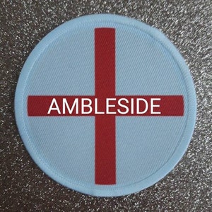 May include: A white round patch with a red cross and the text "AMBLESIDE" in the center.
