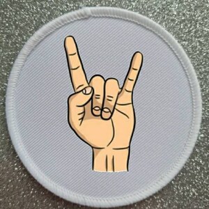 Puede incluir: Parche redondo blanco para planchar con una mano de dibujos animados haciendo el gesto de rock and roll.