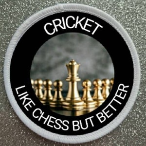 May include: White round patch with black border and white text that reads "Cricket like chess but better". The center of the patch features a photo of gold chess pieces on a gray background.