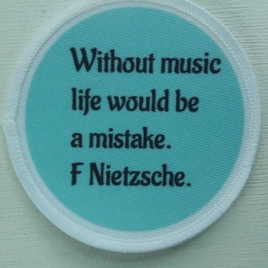 Könnte beinhalten: Ein runder weißer und blauer Patch mit dem Zitat "Ohne Musik wäre das Leben ein Fehler. F Nietzsche."